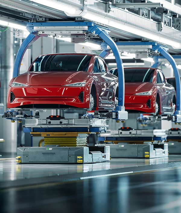 Two red cars on an assembly line.
